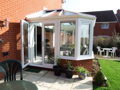 Side image of a Livin room conservatory with white french doors and windows.